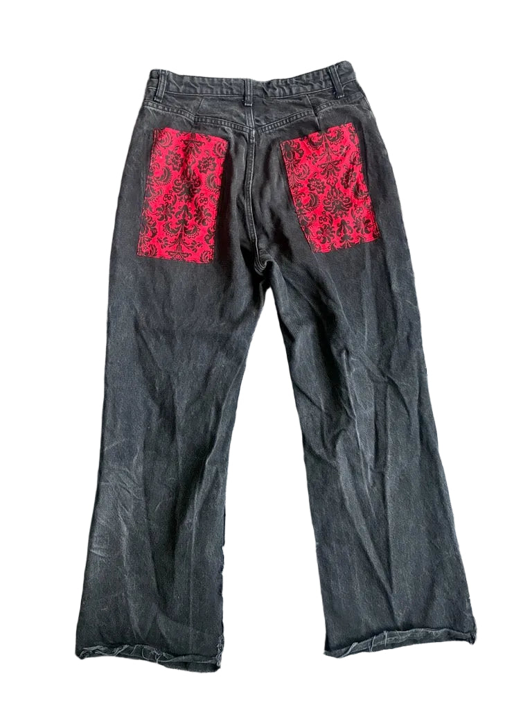 Black pants with red lace patches on a gray textured surface