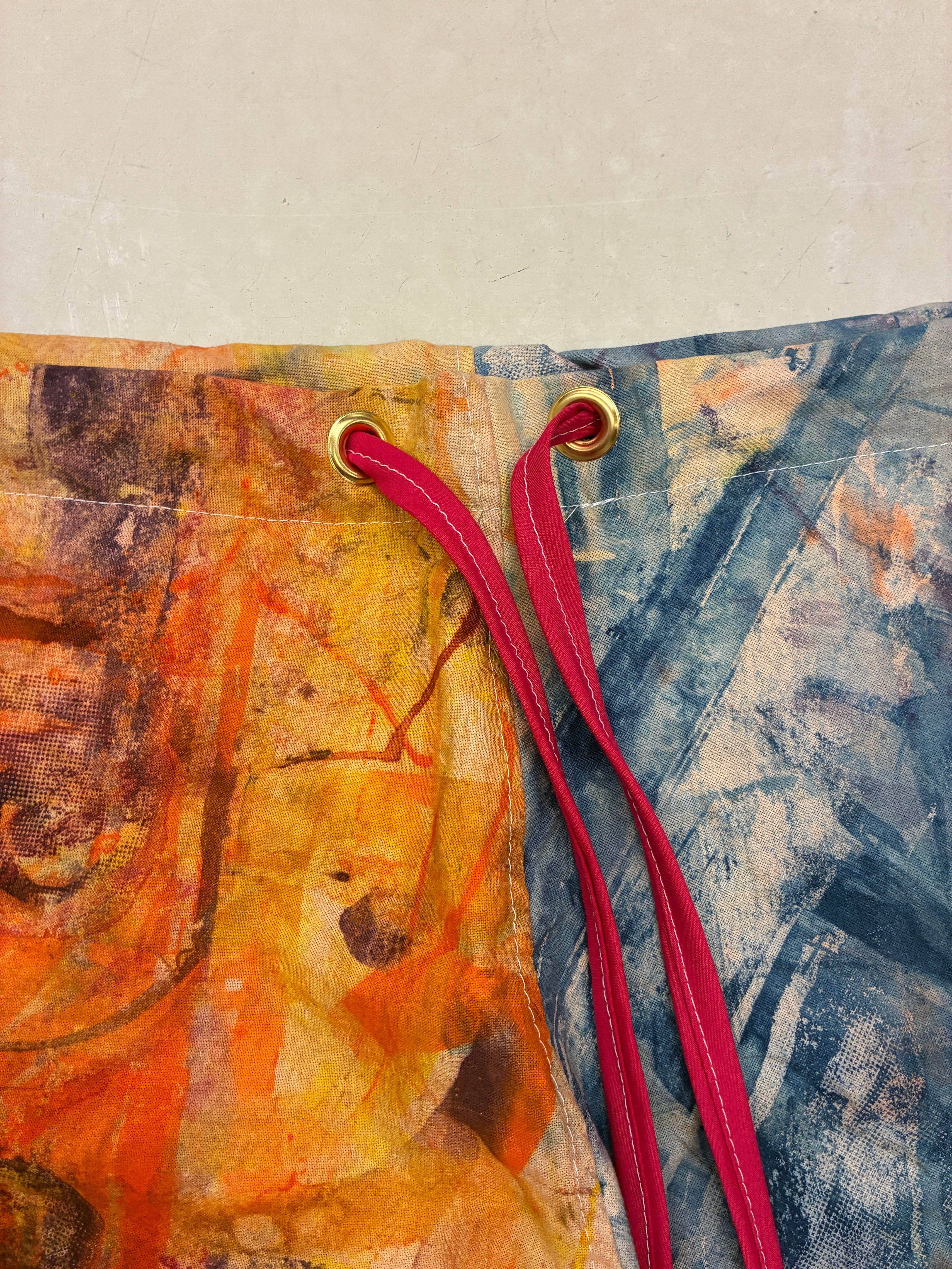 Colorful fabric with a textured pattern and red drawstring on a neutral background