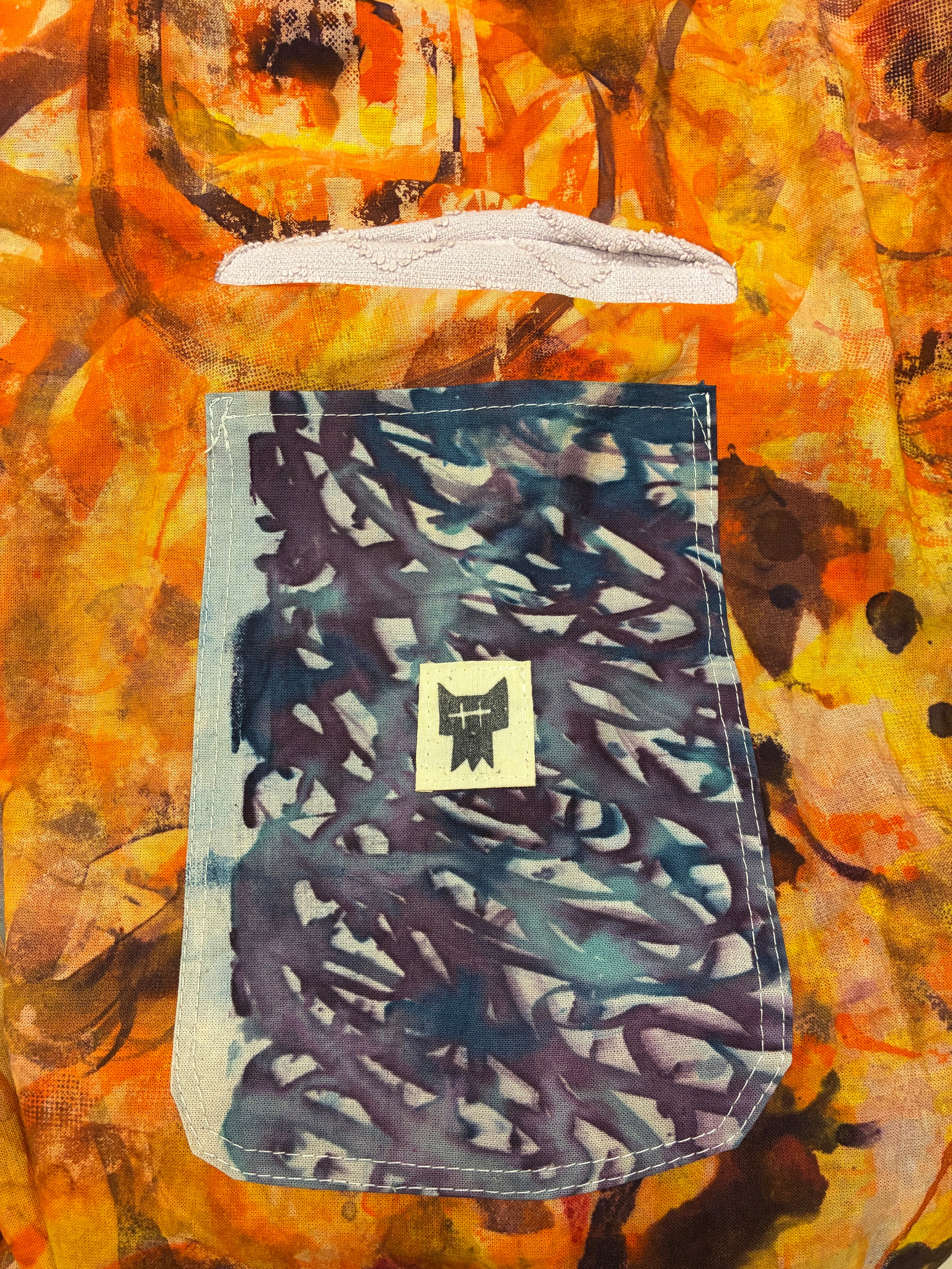 Blue patterned pouch with a logo on a colorful abstract background